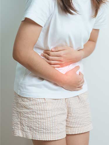Woman holding her stomach and smiling, symbolizing improved gut health and reduced bloating after functional medicine care.