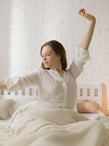 Peaceful woman stretching in bed after a good night’s sleep, reflecting improved mood and mental clarity.